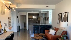 A modern living room with a sofa, coffee table, and dining area. - Monthly Luxury Loft - Old Town (Fort Collins)