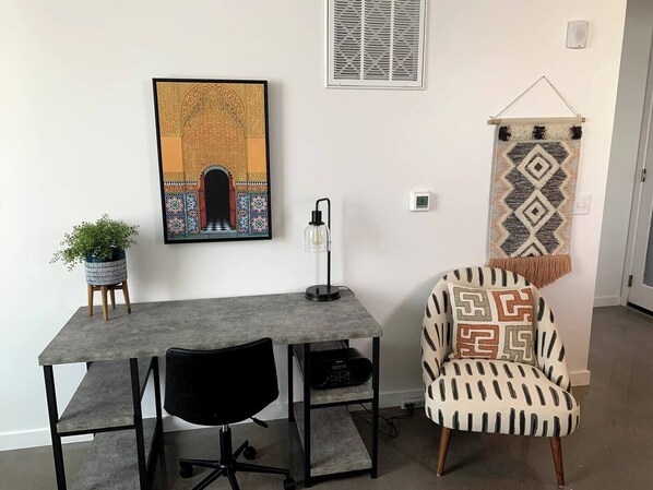 A modern office space with a desk, chair, and decorative items including a framed artwork and a wall hanging.