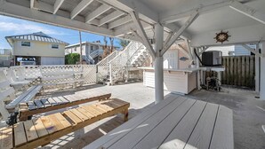 En overdækket terrasse med træbænke og en trappe til en etage over.