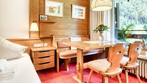 Una habitación con paneles de madera, una cama, una mesa de madera, sillas, una lámpara y cuadros enmarcados en la pared.