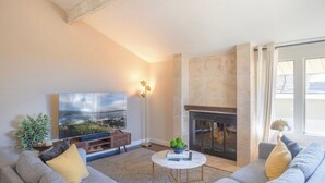 Una sala de estar con chimenea, televisor de pantalla plana y sofá.
