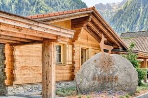 Una cabaña de madera con un letrero de piedra que dice "ANDAM" y una escultura de ciervo de madera.