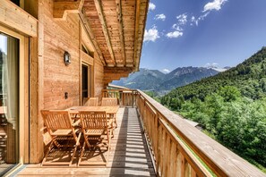 A wooden deck with a table and chairs, overlooking a mountainous landscape. - Dahoam Appartments 3-zimmer mit Balkon Loisch (Buerserberg)