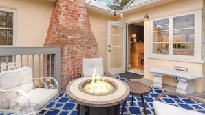 A patio with a fire pit, outdoor seating, and a brick chimney. - Carmel Charmer - Close to Downtown w/ Fire Pit! (Carmel-by-the-Sea)