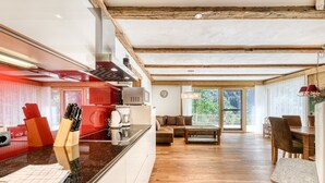 Una cocina moderna con una isla central, vigas de madera y un comedor con vistas.