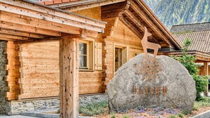 Una cabaña de madera con un letrero de piedra que dice "ANDAM" y una escultura de ciervo de madera.
