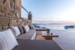 A stone-walled room with a built-in sofa and a small table with a plant.