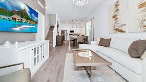 Ein modernes Wohnzimmer mit einem weißen Sofa, einem Couchtisch und einem an der Wand befestigten Fernseher.
