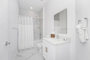 A modern bathroom with a shower, toilet, and vanity. - Family 5BR Retreat Near Disney + Pool (Davenport)