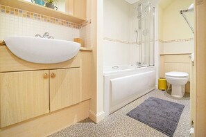 Une salle de bain avec un lavabo blanc, une baignoire et des toilettes.