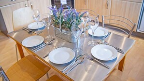 A dining table set with white plates, silverware, and wine glasses, centered with a decorative flower arrangement. - Bannermill Place Apartment | Grampian Lettings Ltd (Aberdeen)