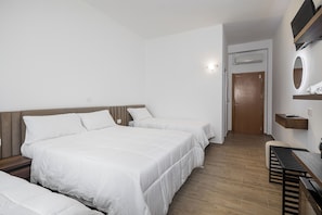 Comfortable accommodations feature a large bed and two additional beds, a wooden bench, and a small table with a chair.
