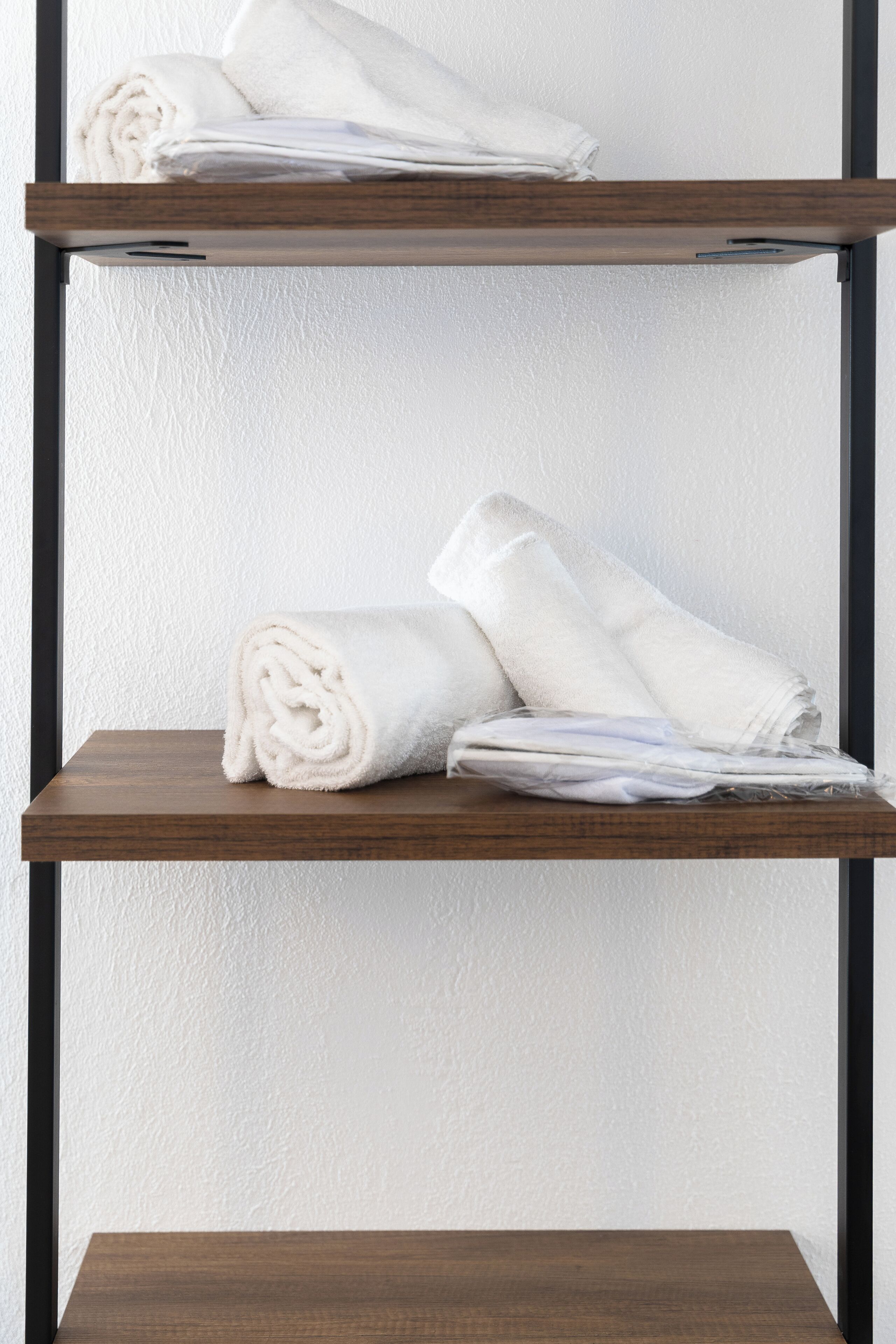 A wooden shelf with neatly folded white towels.