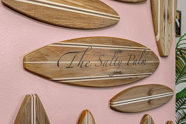 A wall with wooden surfboard-shaped plaques, one of which reads "The Sally Palm." - The SALTY PALM Coastal Retreat, sleeps 13! Resort-Inspired POOL & Themed Rooms (Palm Bay)