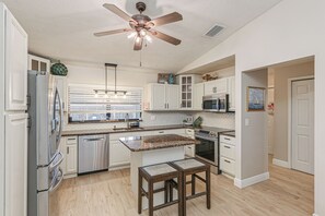 Uma cozinha moderna com armários brancos, eletrodomésticos de aço inoxidável e uma ilha central.