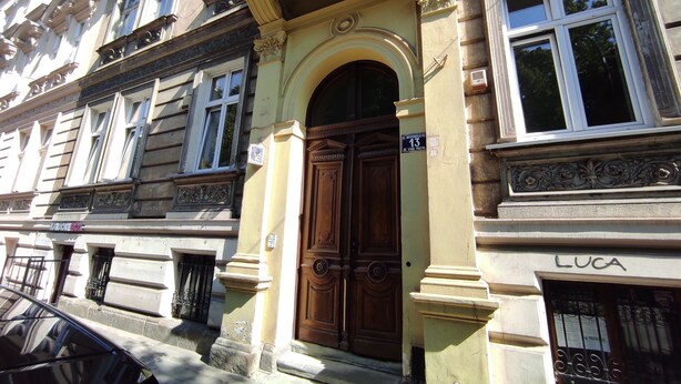 Un edificio con una puerta grande de madera, un letrero que dice "KARATEK 80" y el nombre "LUCA" a la derecha.