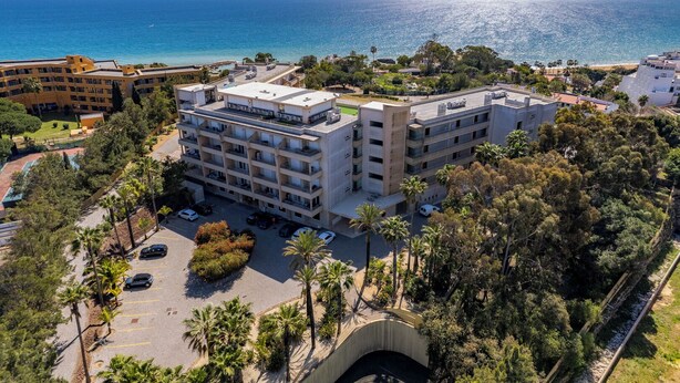 Un hotel a più piani con balconi affacciati su una spiaggia e il mare.