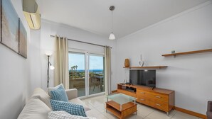 Un soggiorno moderno con divano, tavolino, televisione e un balcone con vista.