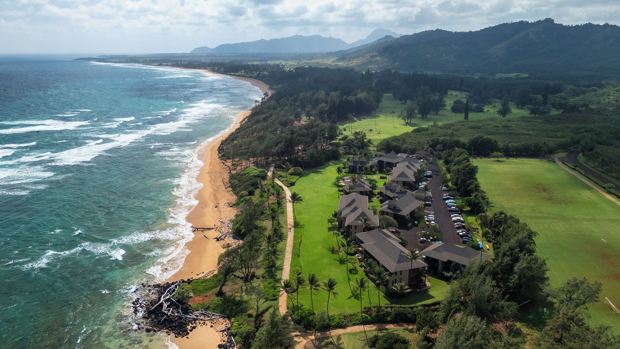 A coastal resort with beachfront properties, a golf course, and lush greenery.