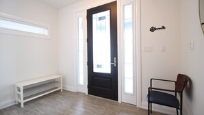 Une pièce avec une porte noire, un banc blanc et une chaise.