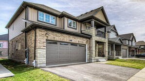 Une maison à deux étages avec un garage, une façade en pierre et un toit en pente.