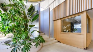 Ein modernes Interieur mit einer geschwungenen Treppe, einem Holzschrank mit Glastür und üppigem Grün.