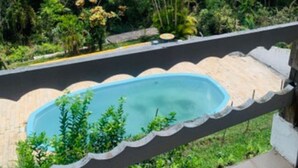 Ein Pool mit Blick auf eine üppige Landschaft und sanfte Hügel in der Ferne.