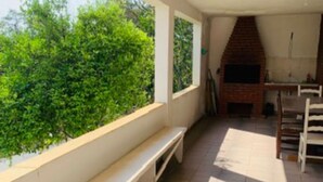 Eine Außenpatio mit einer Bank, einem Kamin aus Ziegeln und Blick auf Grünflächen.