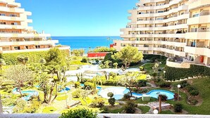 Udsigt over et resort med flere bygninger, en swimmingpool og en klar blå himmel.