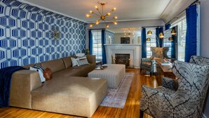 A living room with a sectional sofa, patterned armchair, and a fireplace. - Luxurious Mid-Century-Retreat (Ogden)