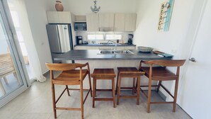 A modern kitchen with wooden chairs, a refrigerator, a microwave, and a sink.