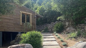 Une cabane en bois rustique, avec un sentier de pierres menant à un mur de pierres.