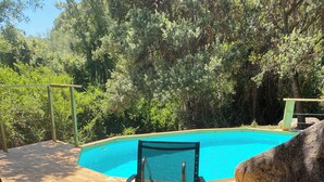 Une terrasse en bois avec une piscine, une chaise et une table.