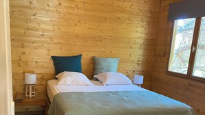 Une chambre aux murs lambrés, avec un lit, des oreillers et une table de chevet.
