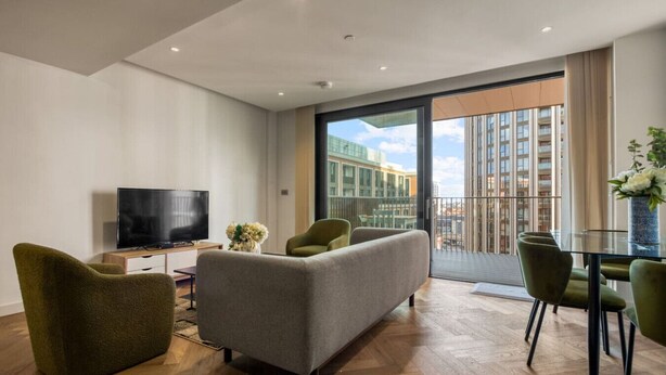 A modern living room with a flat-screen TV, a sofa, and a dining table with chairs. - Hyde Park Elegenace 2BR 2BA Balcony (London)