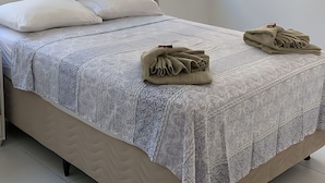 A neatly made bed with a patterned bedspread, two pillows, and two folded towels on the bed. - Casa Encanto da Barra (Barra de São Miguel)