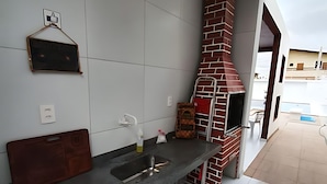 A modern kitchen with a built-in brick oven, a granite countertop, and a small sink. - Casa Encanto da Barra (Barra de São Miguel)