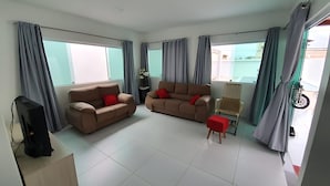 A modern living room with two sofas, a TV, and a small table. - Casa Encanto da Barra (Barra de São Miguel)
