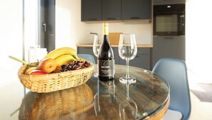 A dining table with a bottle of Escher wine, two glasses, and a basket of fruits. - Brenztal Eco Lodge (Giengen an der Brenz)