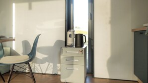 A small kitchenette with a coffee maker, a chair, and a cabinet. - Brenztal Eco Lodge (Giengen an der Brenz)