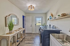 A laundry room with a washing machine, a drying rack, and a mirror.