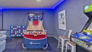 Una habitación con una canasta de baloncesto, un dardo y una máquina de juegos.