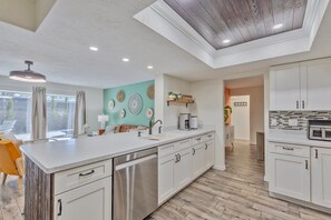 A modern kitchen with a central island, stainless steel appliances, and a view to the outside.