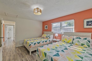 A bedroom with two beds, a window with blinds, a ceiling light fixture, and a door leading to another room.