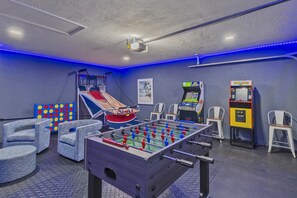 A room with a foosball table, a basketball hoop, and arcade games. - Seminole Pool House with Game Room and Fire Pit (Seminole)