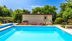 A swimming pool with a stone deck, surrounded by vibrant flowers and greenery. - Villa Relax with pool&beachfront by Villas Guide (Bakar)