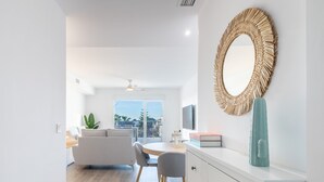 Un salon moderne avec un coin repas, un grand miroir et une vue sur l’extérieur.