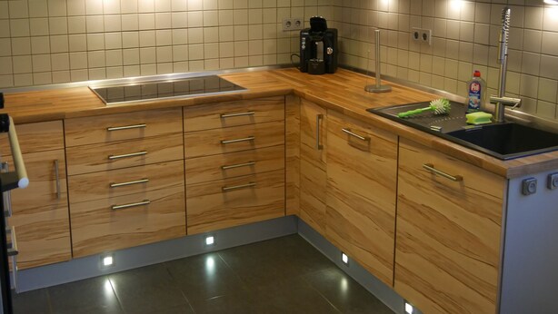 A modern kitchen with wooden cabinets, a stainless steel sink, and a built-in oven. - Vacation cottage Baarsen 30 (Bad Pyrmont)