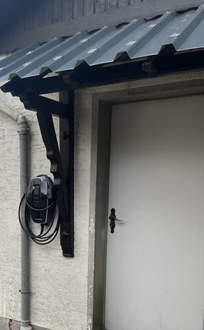 Fachada de edificio con puerta de garaje, un poste de electricidad y un cable enrollado.