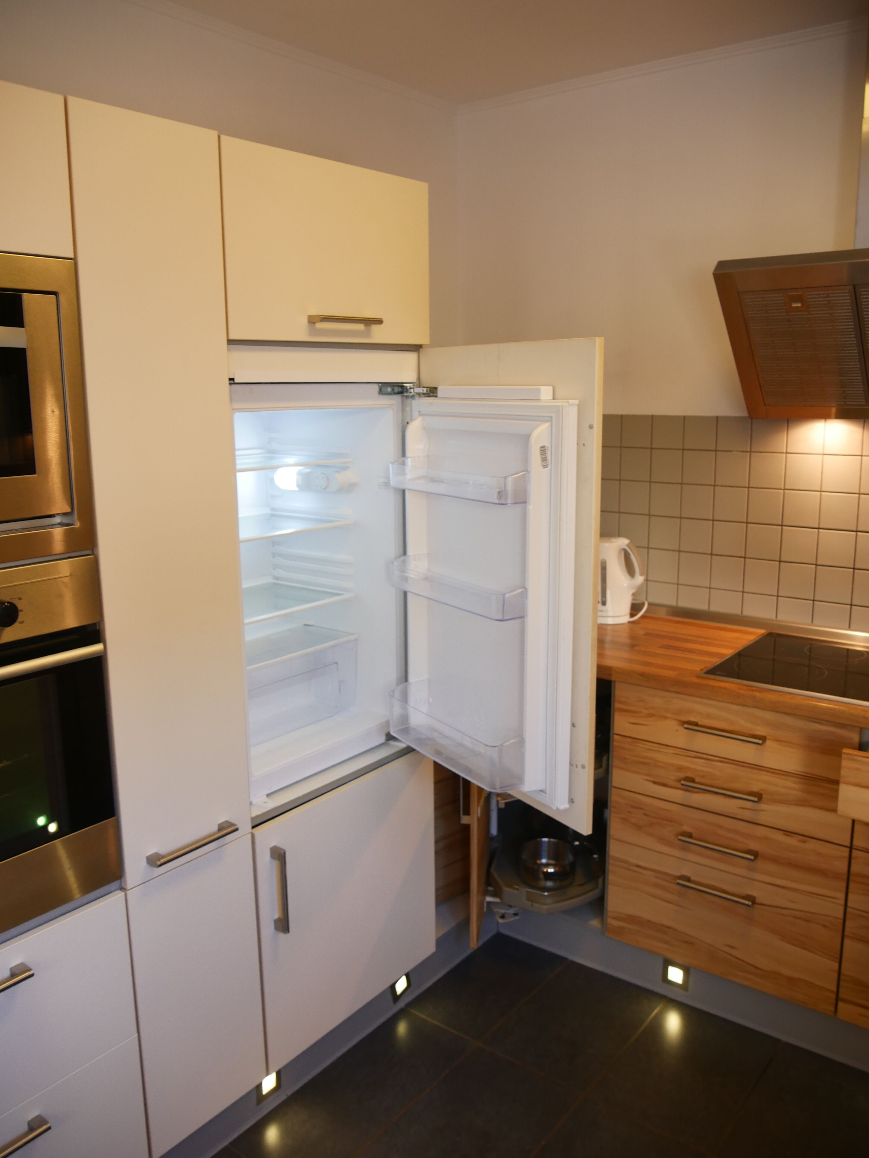 A modern kitchen with a built-in refrigerator, oven, and wooden cabinets.